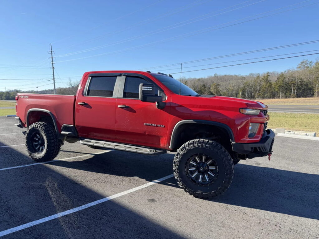 Red lifted Chevrolet Silverado 2500 HD parked outdoors.